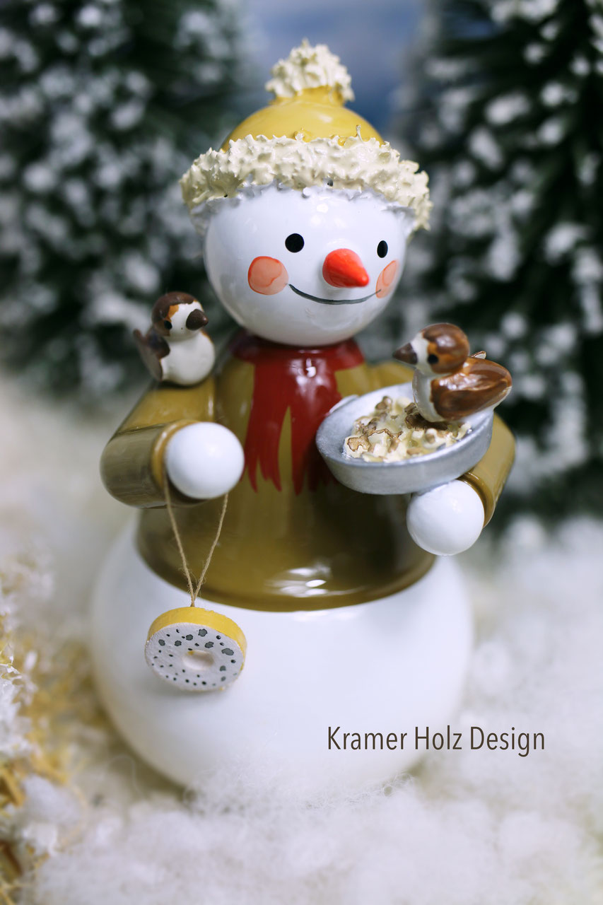 Schneemann mit Futterschale und Vögeln